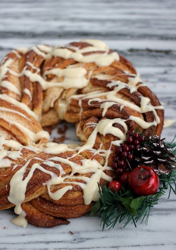 beautifully decorated holiday cinnamon roll loaf with thick white icing on a festive table