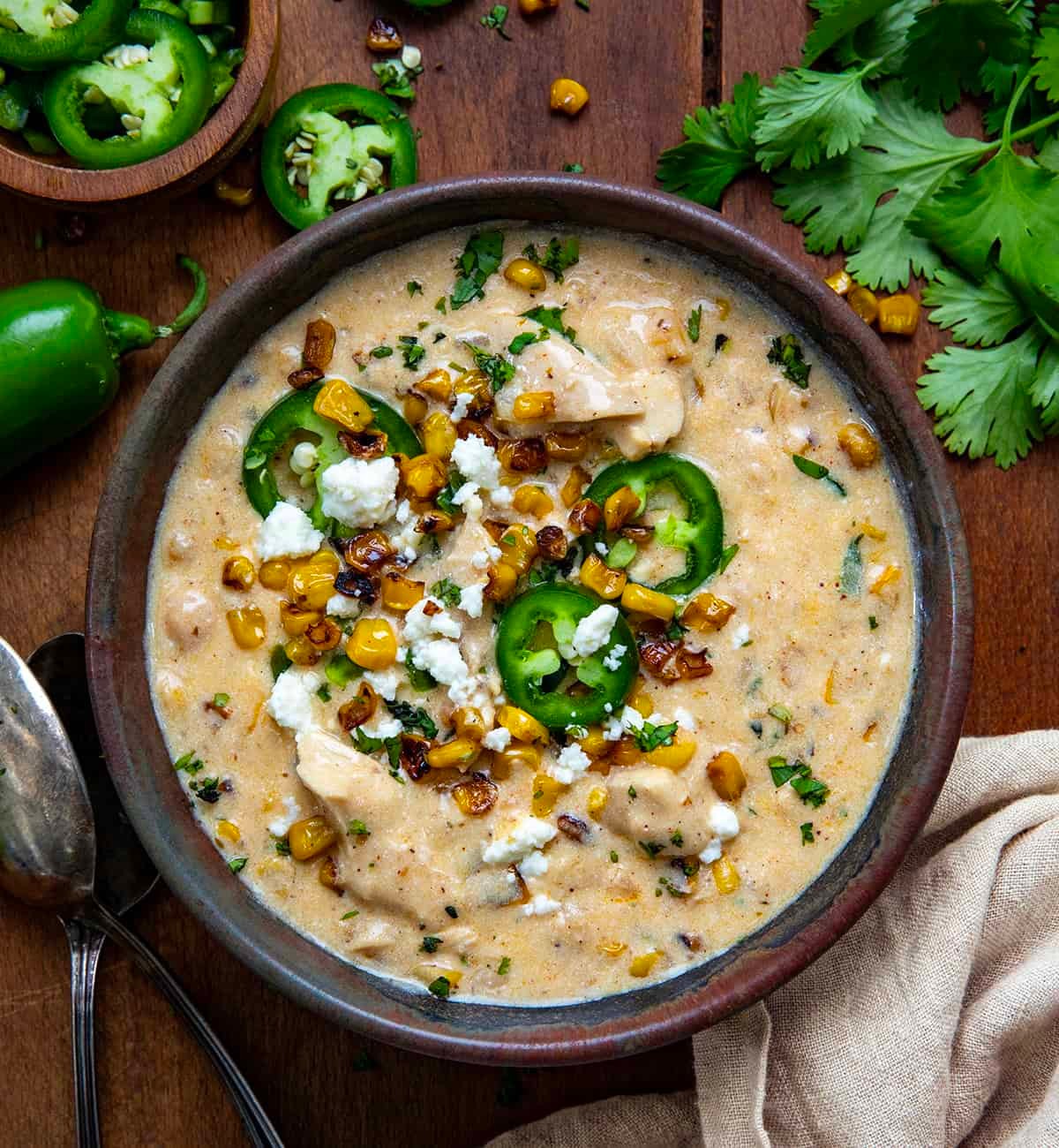 hearty bowl of white chicken chili with roasted corn, garnished with fresh cilantro and a dollop of sour cream, served in a cozy kitchen setting