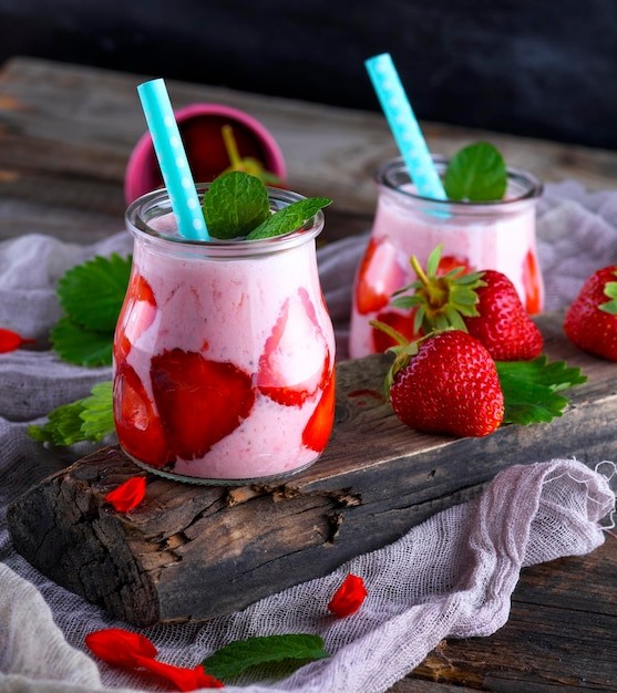 A refreshing Strawberry Lassi in a tall glass, garnished with fresh strawberries and mint leaves, with a backdrop of a bright, sunny kitchen