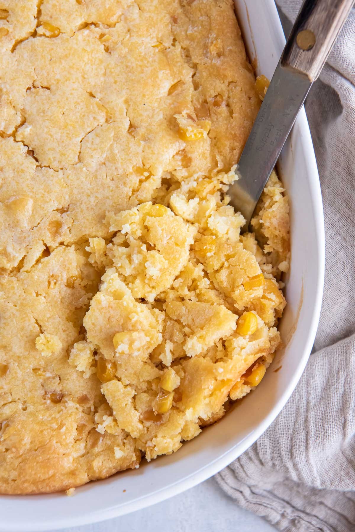 Delicious golden corn casserole with a crispy top, served in a rustic farmhouse setting