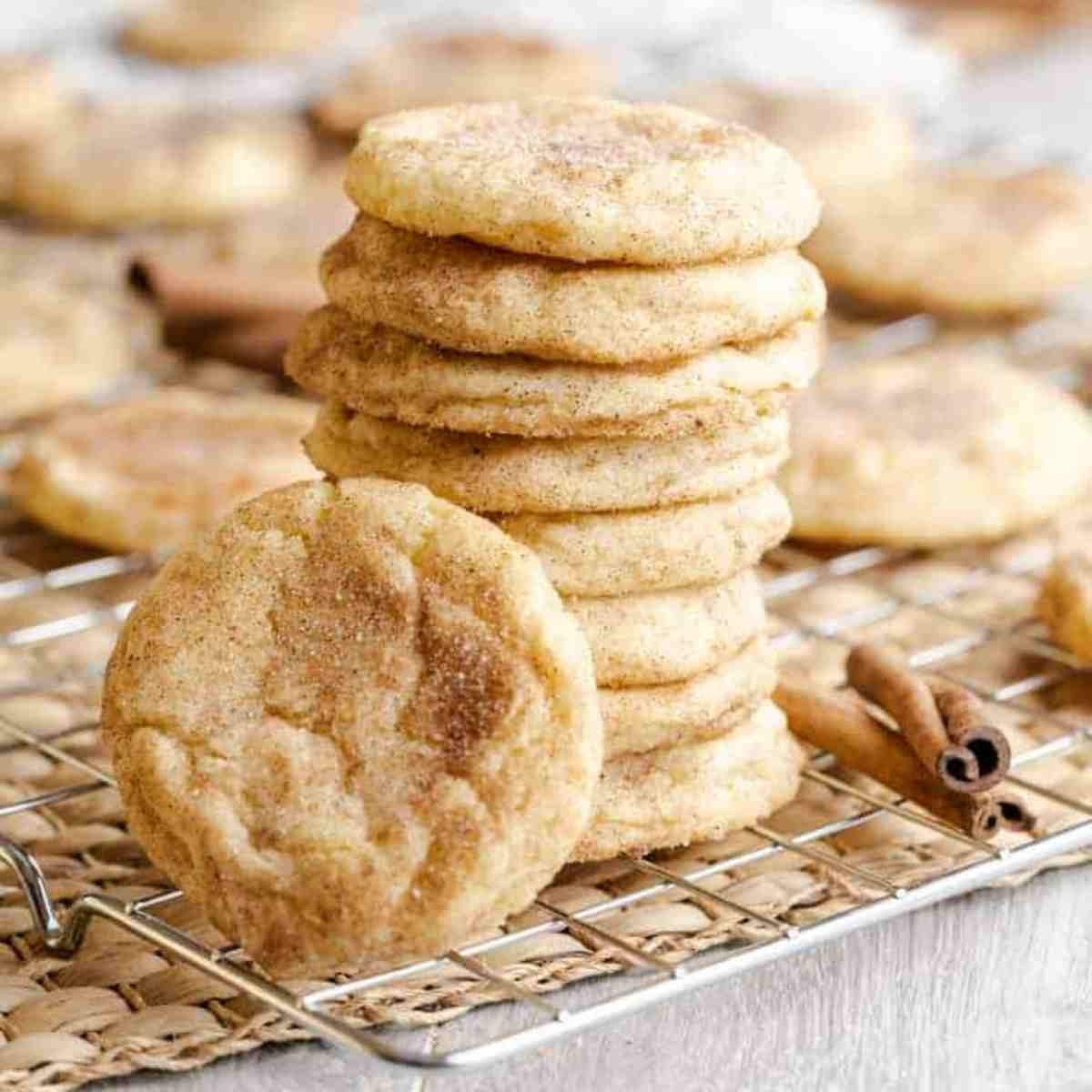 Warm snickerdoodle cookies on a cooling rack, dusted with cinnamon sugar, with a cozy kitchen background