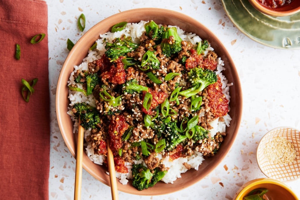 vibrant chili-glazed beef bowl with broccoli and rice, garnished with sesame seeds