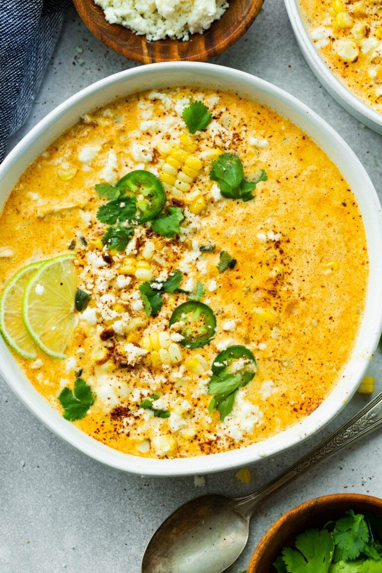 a steaming bowl of Mexican street corn soup topped with cilantro and a lime wedge