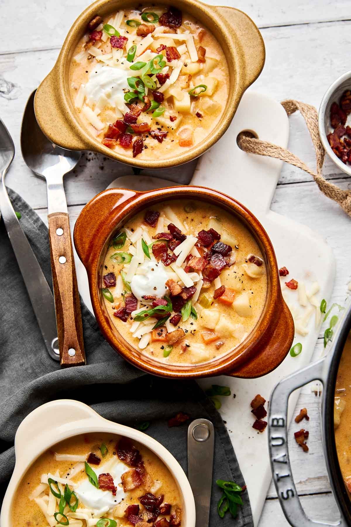 Hearty potato soup bowl with crispy bacon bits and fresh green scallions on top