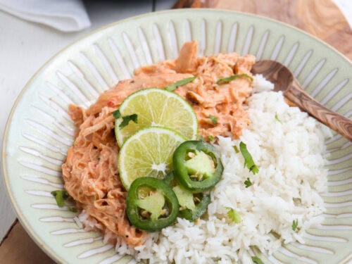 Crockpot salsa chicken served with rice and cilantro, close-up, warm lighting