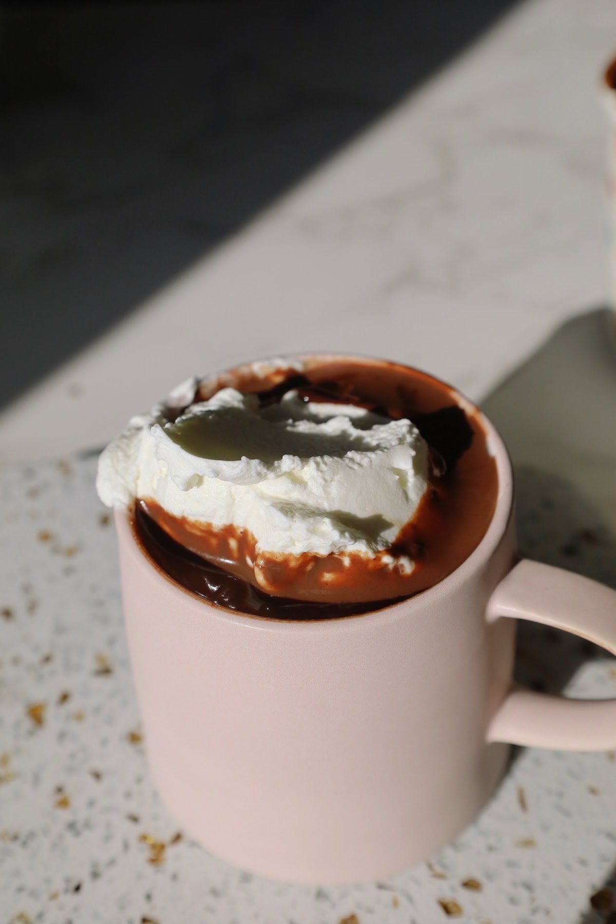 luxurious creamy hot chocolate with generous whipped cream and chocolate shavings in a cozy mug, soft lighting