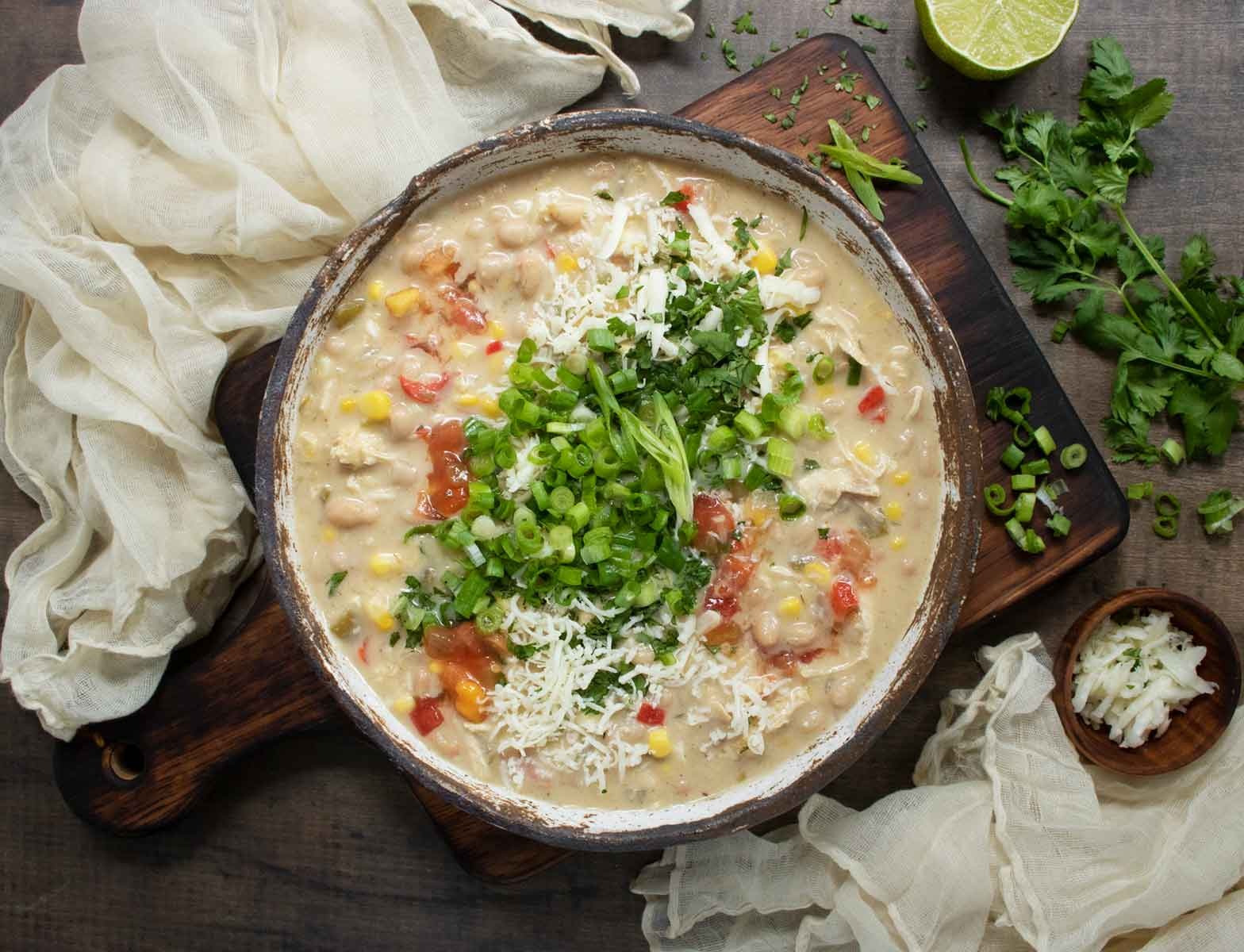 Cozy bowl of white chicken chili topped with roasted corn and fresh cilantro on a rustic wooden table