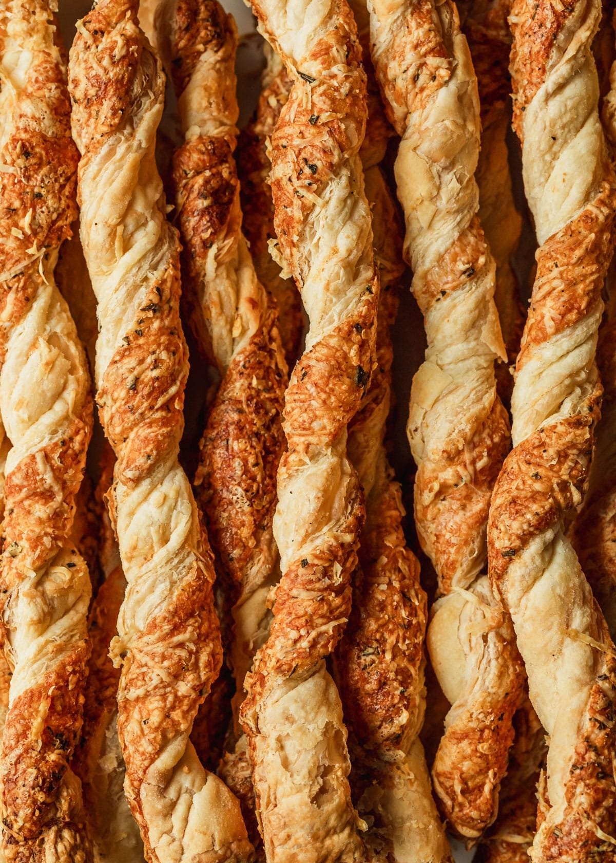 Golden brown parmesan puff pastry twists on a baking sheet, close up
