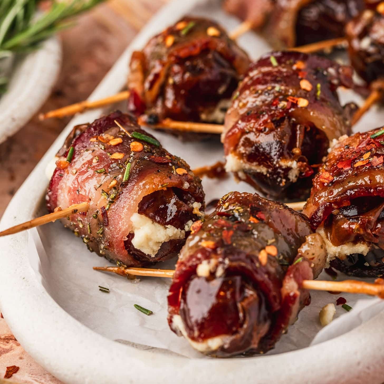 Delicious close-up of bacon wrapped dates with a sticky glaze on a serving platter, warm lighting, inviting