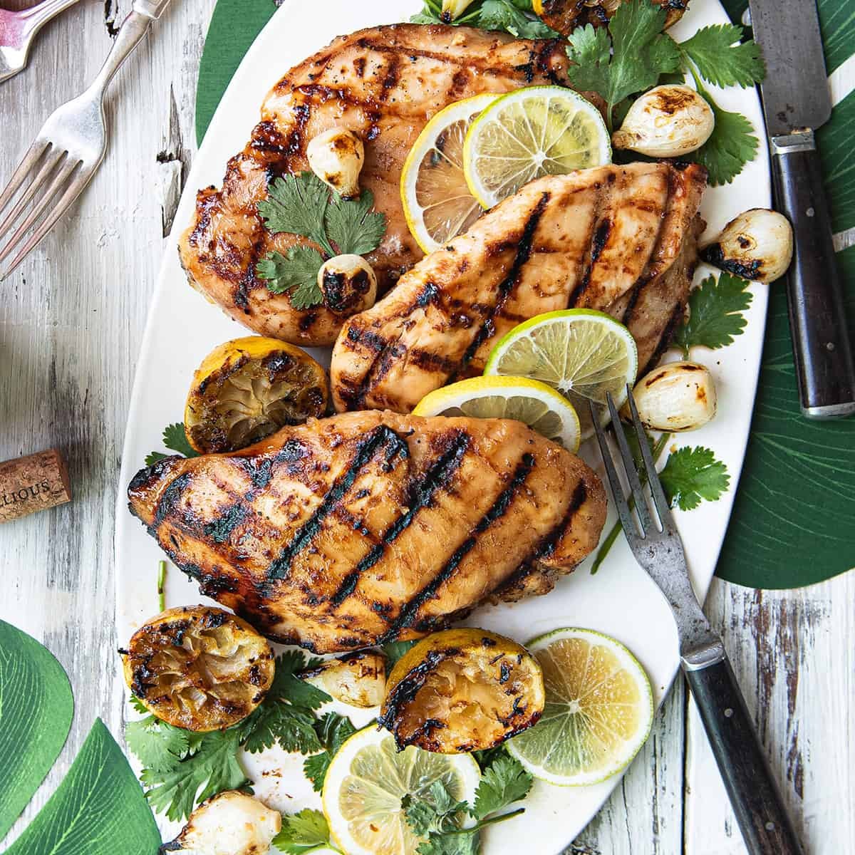 Grilled chicken breast with fresh lemon, orange slices, and herbs on a BBQ grill, vibrant and juicy