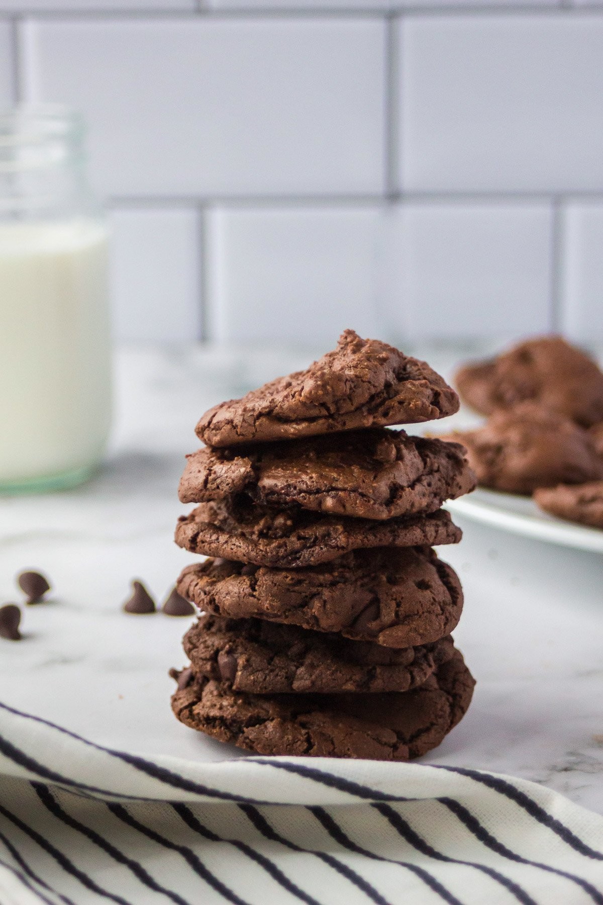 Warm double chocolate cookies stacked on a cooling rack, gooey chocolate chips visible, next to a glass of milk