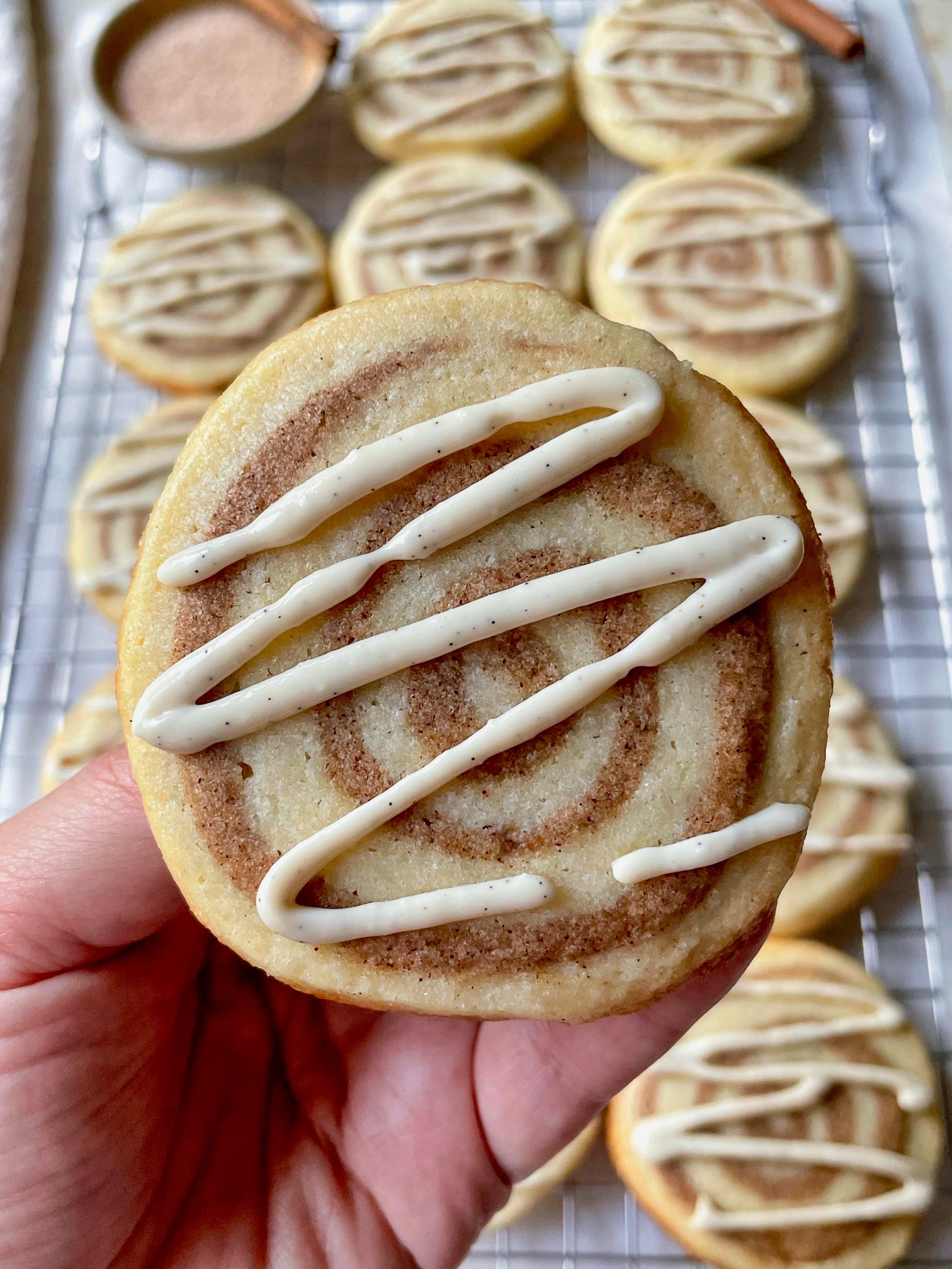 Homemade cinnamon sugar pinwheel cookies cooling on a wire rack, close up, warm lighting