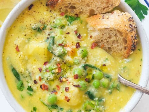 close-up of creamy, rich vegetable soup in an elegant bowl with crusty bread, bistro lighting