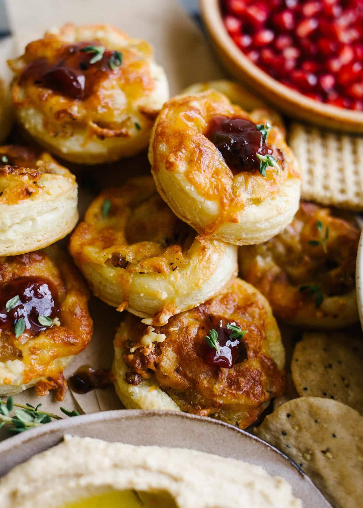 Golden brown savory cheese puffs piled high on a rustic wooden board, with a sprinkle of herbs