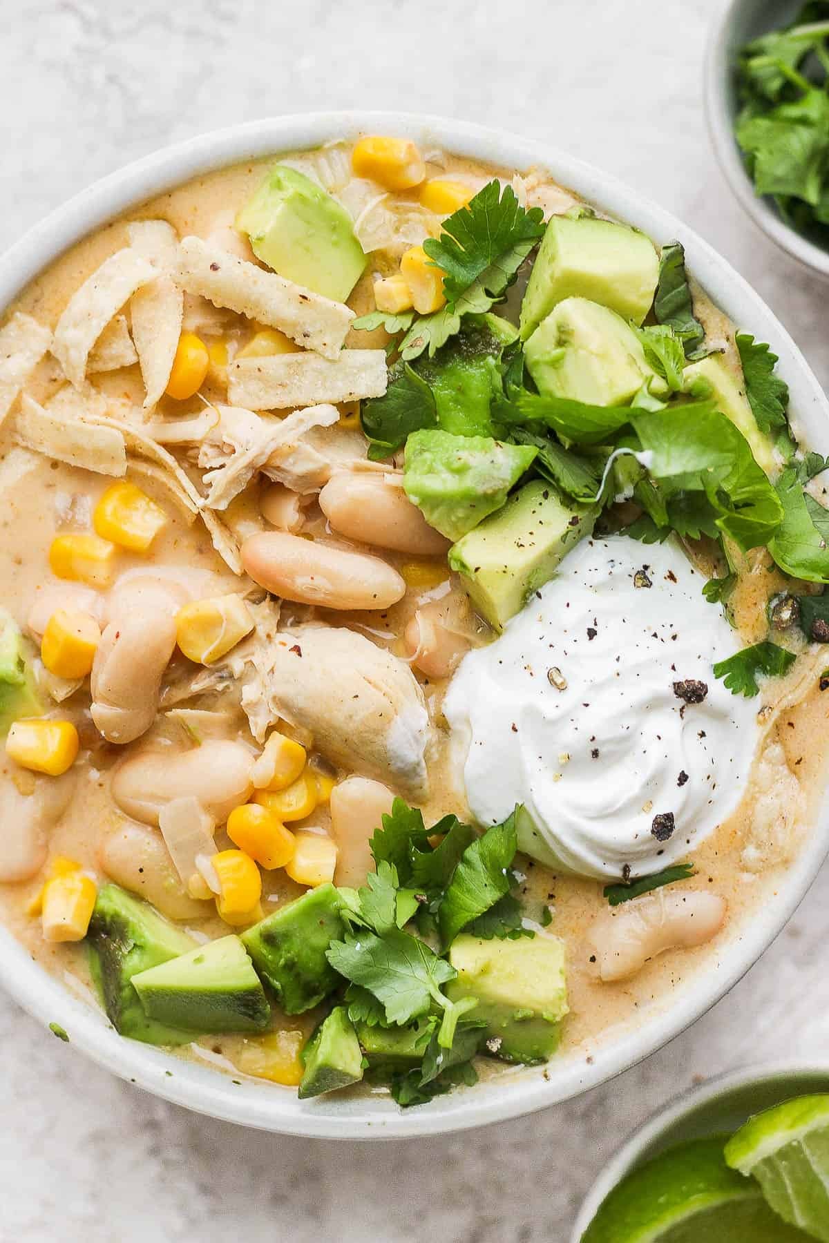 Creamy white chicken chili skillet with corn and beans, garnished with cilantro, in a cast iron skillet on a rustic wooden table
