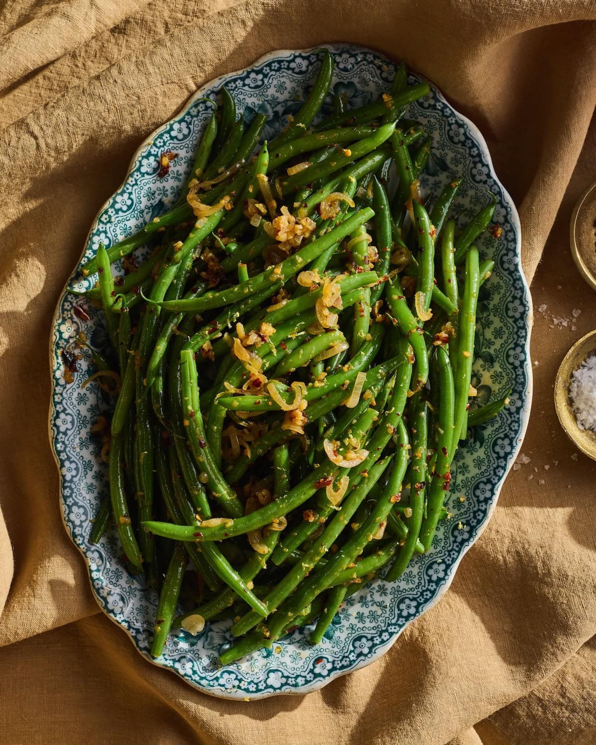 Close-up of crispy garlic green beans in a serving dish, garnished with fresh herbs