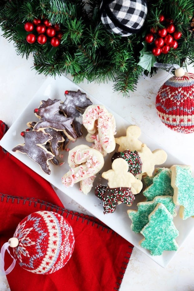 beautifully decorated french tip shortbread cookies shaped like Christmas ornaments on a festive platter