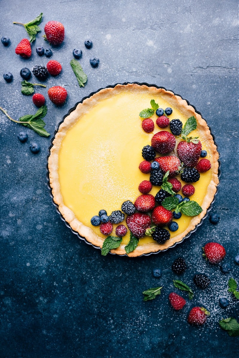 Vibrant lemon custard tart with fresh berries and a golden crust on a rustic wooden table, bright daylight