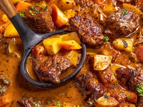 Rustic chili-rubbed beef stew in a cast iron pot, garnished with fresh herbs, steam rising