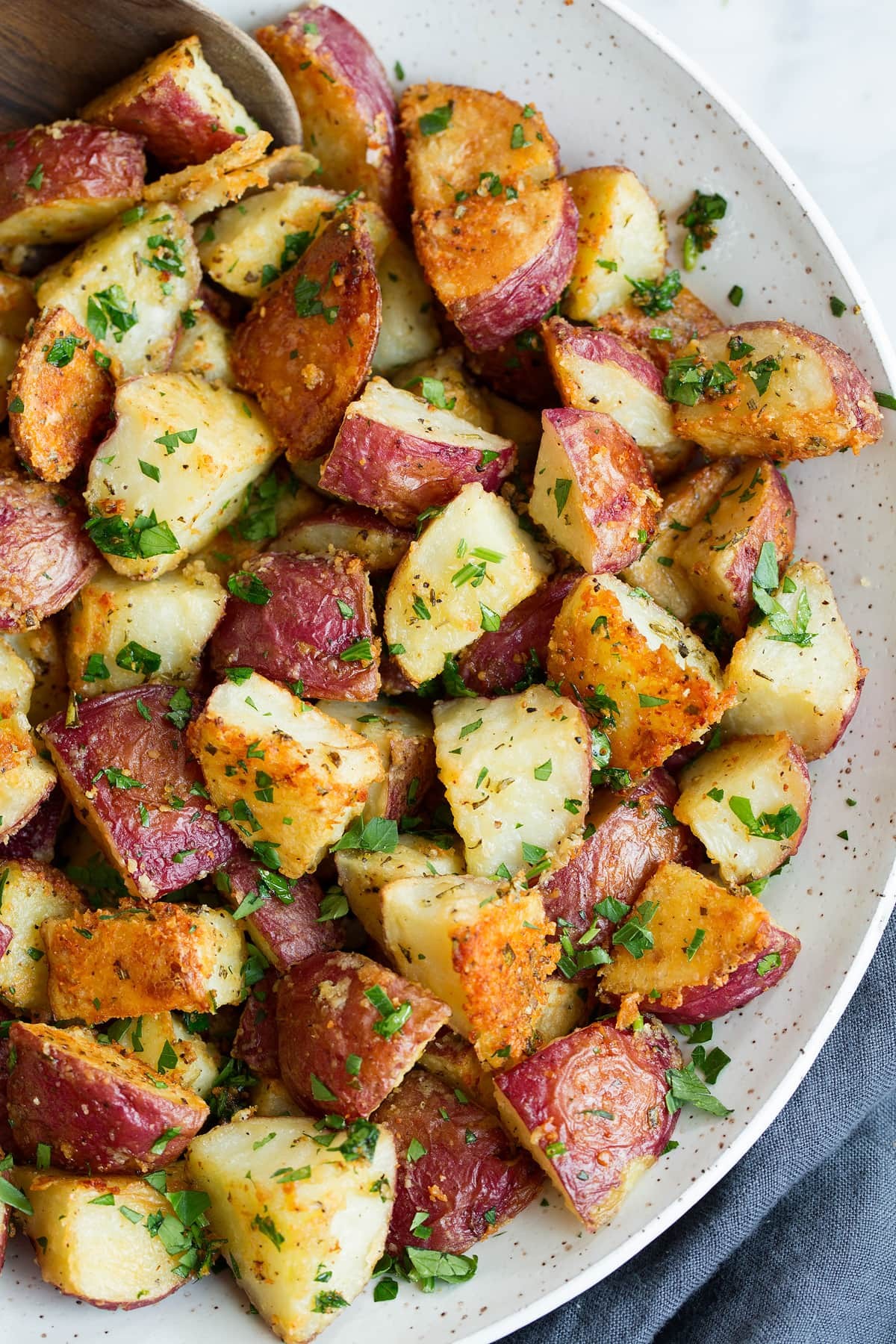 close-up of golden brown parmesan roasted potatoes with fresh herbs