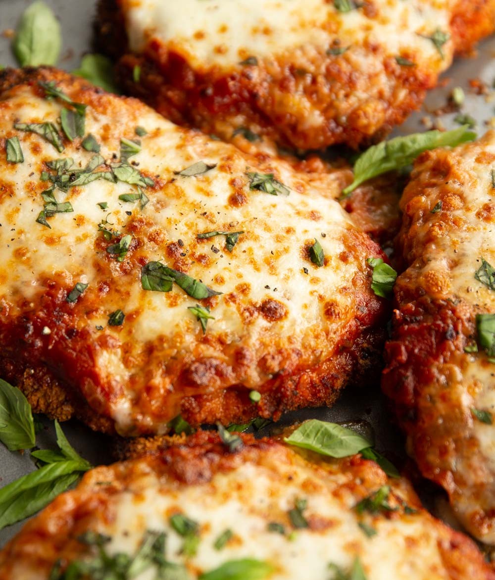 close up shot of chicken parmesan cookies on a wooden board with a sprinkle of fresh parsley