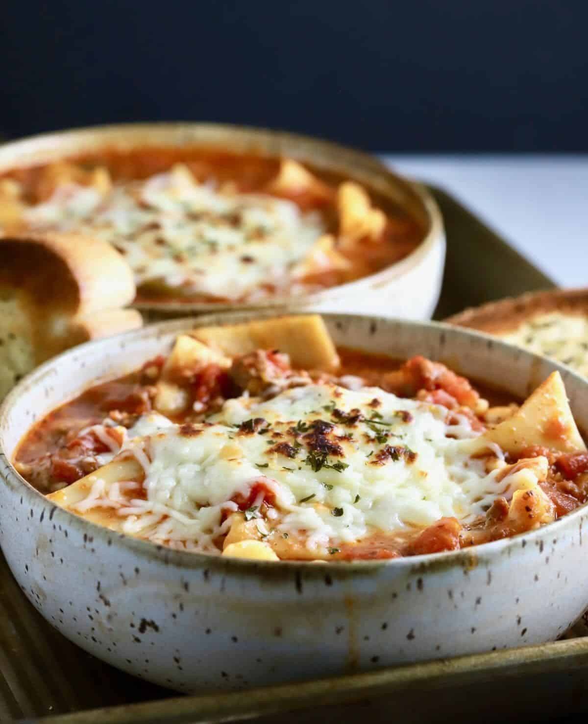 a bowl of steaming lasagna soup topped with cheese
