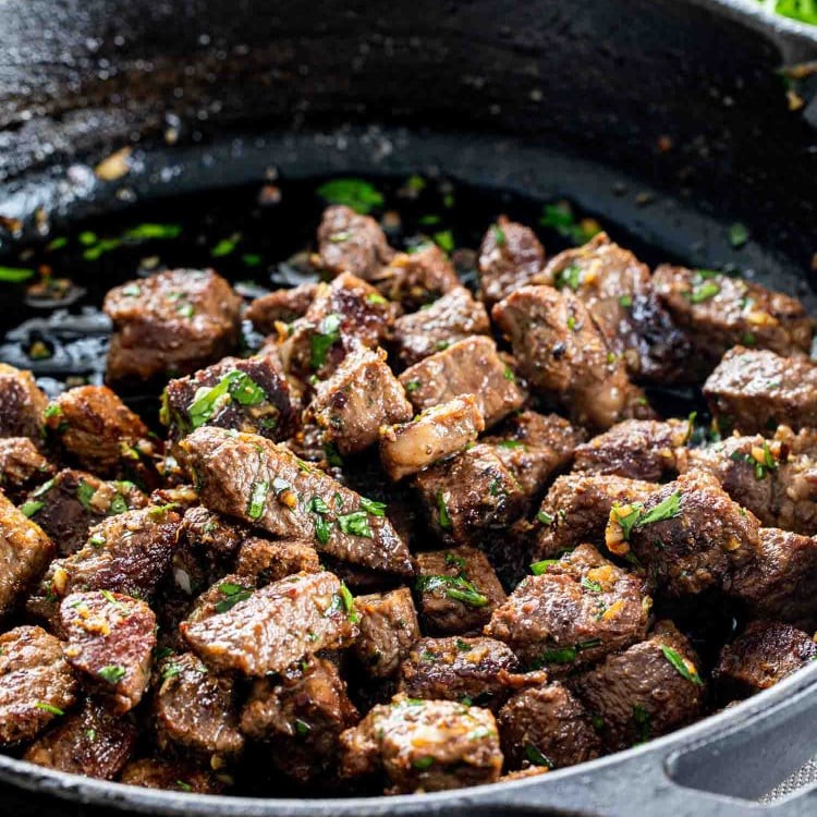 steak bites being cooked in garlic butter in a skillet