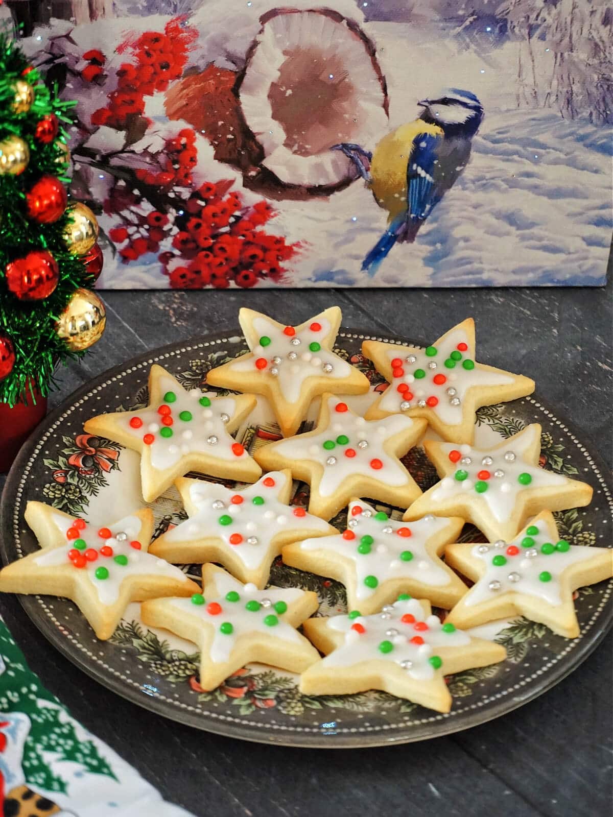 Festive star-shaped sugar cookies with vibrant, shiny glazes on a cooling rack, decorated for a party