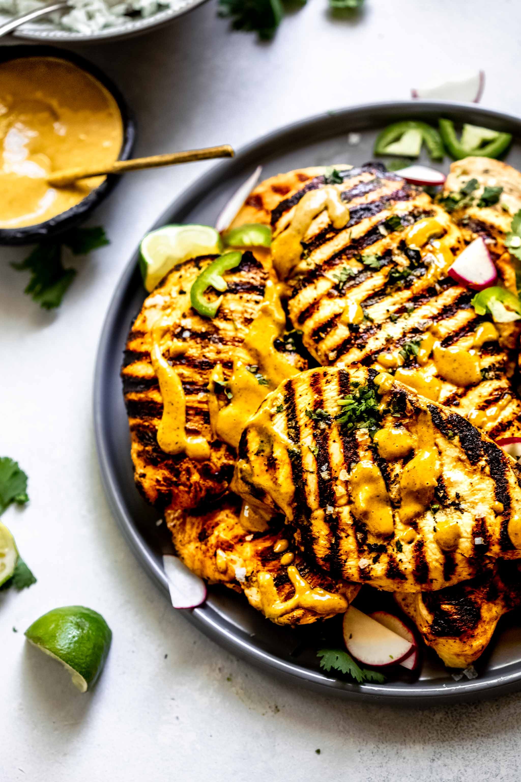 grilled chicken breasts with peanut sauce, cilantro garnish, grilled vegetables