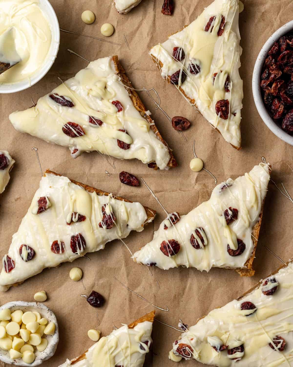Festive cranberry bliss bars on a rustic wooden board, drizzled with white icing, close-up