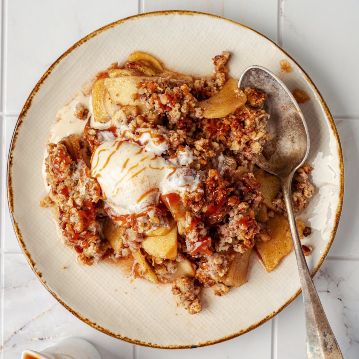 Molten apple crisp crumble with a scoop of vanilla ice cream, close-up, warm lighting
