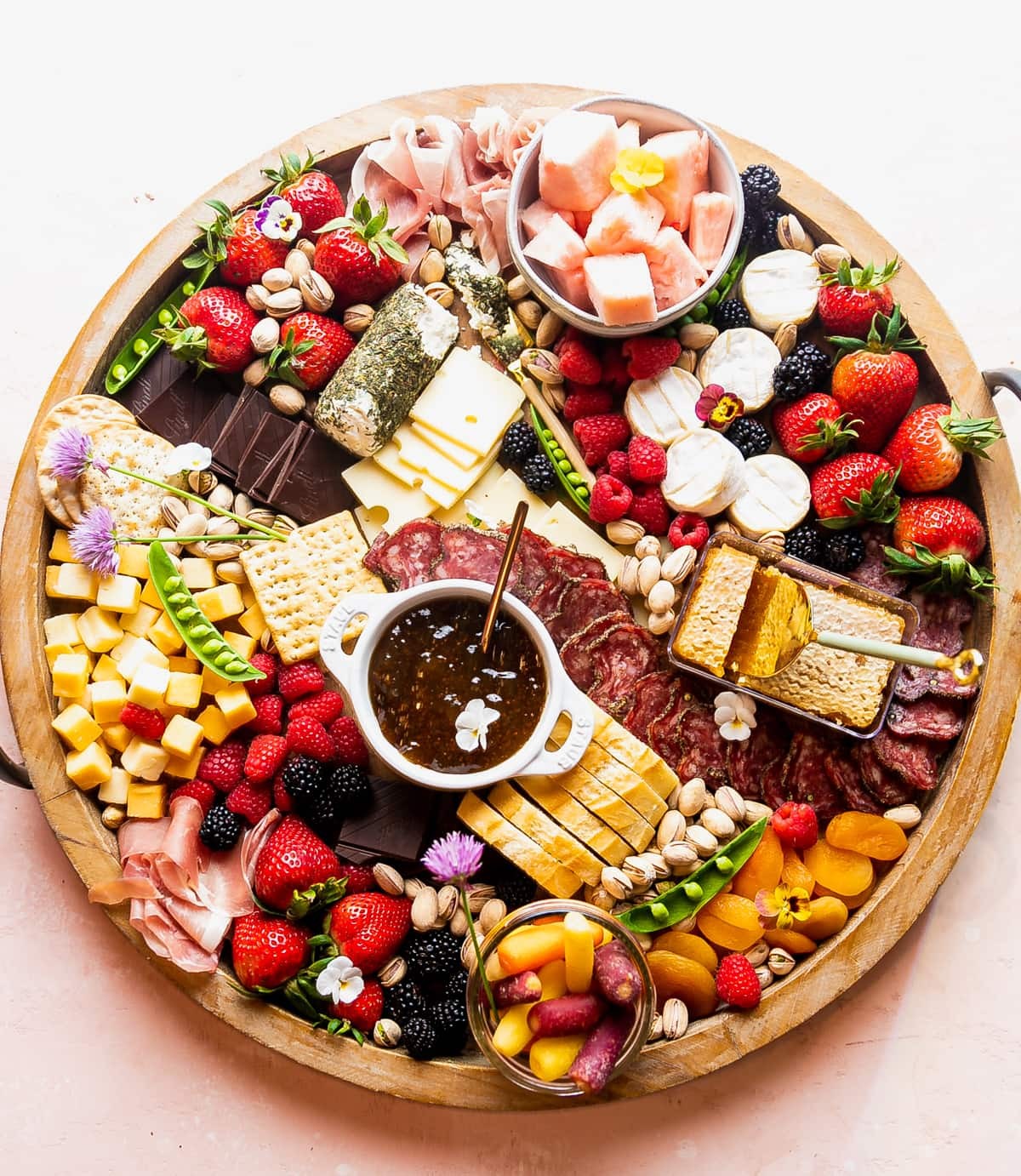 Elegant charcuterie board with honeycomb, brie cheese, figs, grapes, prosciutto, and crackers, beautifully arranged on a wooden board.