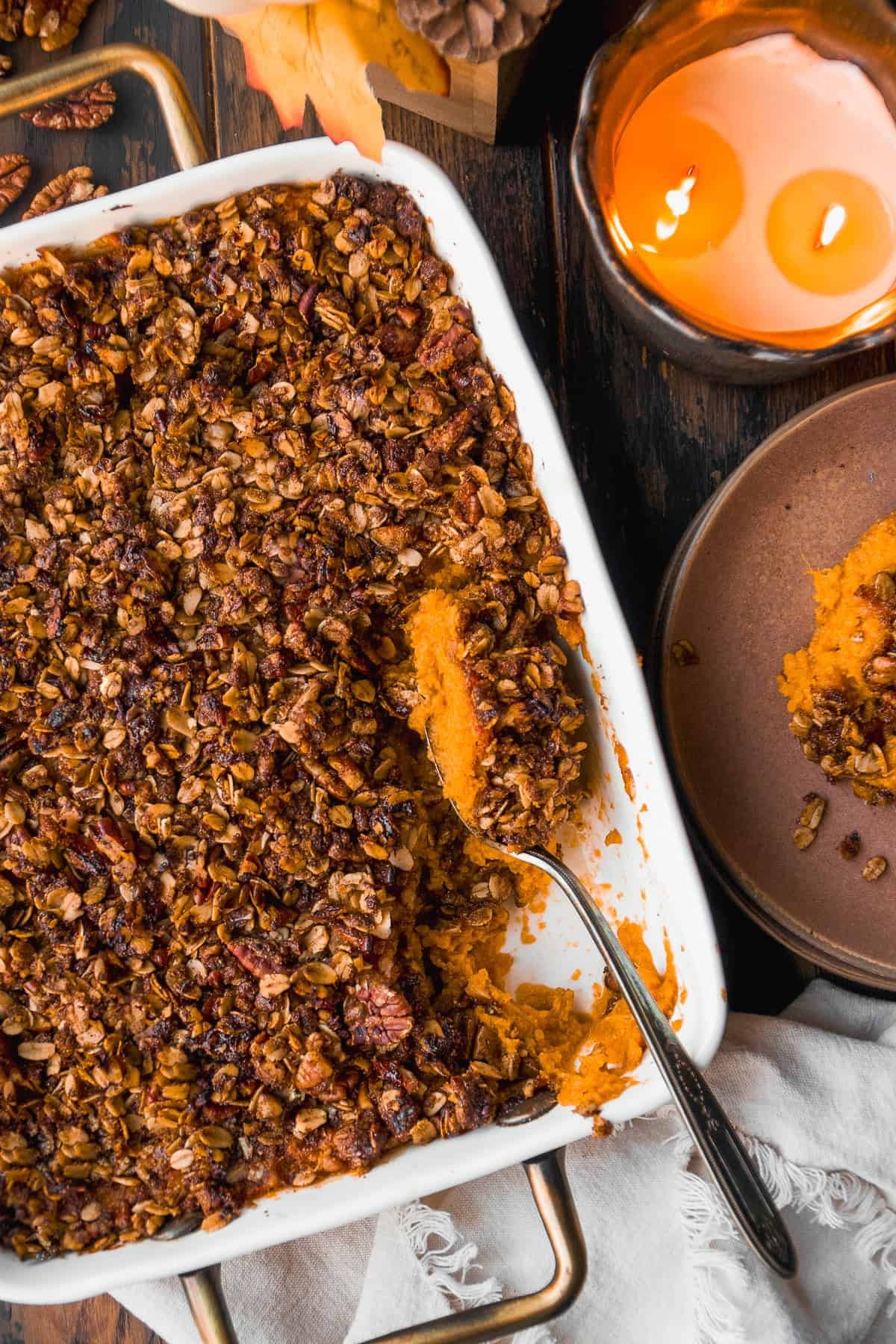 Vibrant maple sweet potato casserole with a golden brown pecan streusel topping, garnished with fresh herbs, shot from above on a rustic wooden table, holiday feast setting