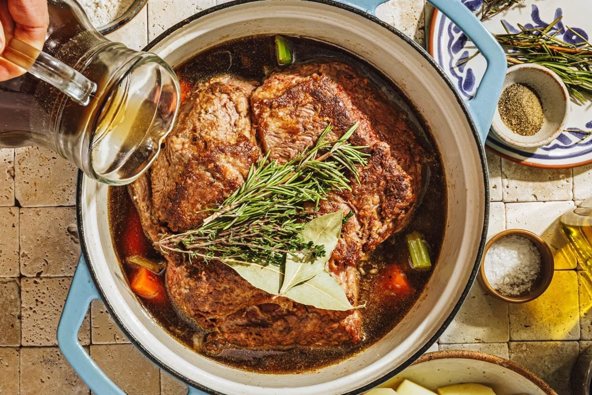 hearty chili-pepper beef roast in a Dutch oven, rustic kitchen