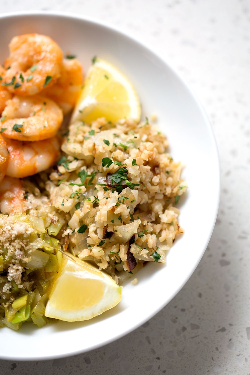 Vibrant cauliflower rice pilaf in a serving bowl, garnished with fresh herbs and a lemon wedge, cozy kitchen background