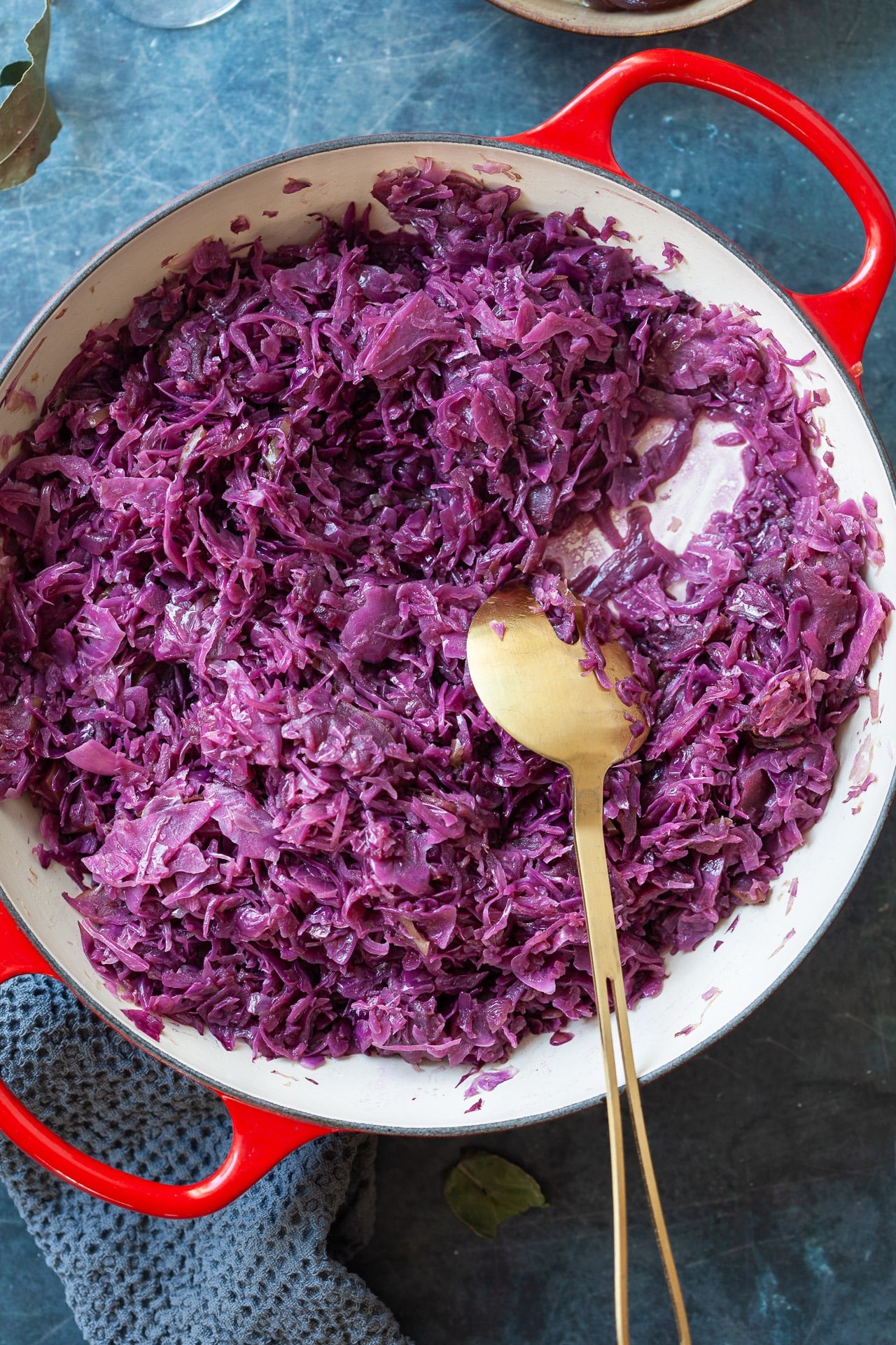 Vibrant braised red cabbage in a serving dish, steam rising, garnished with fresh herbs