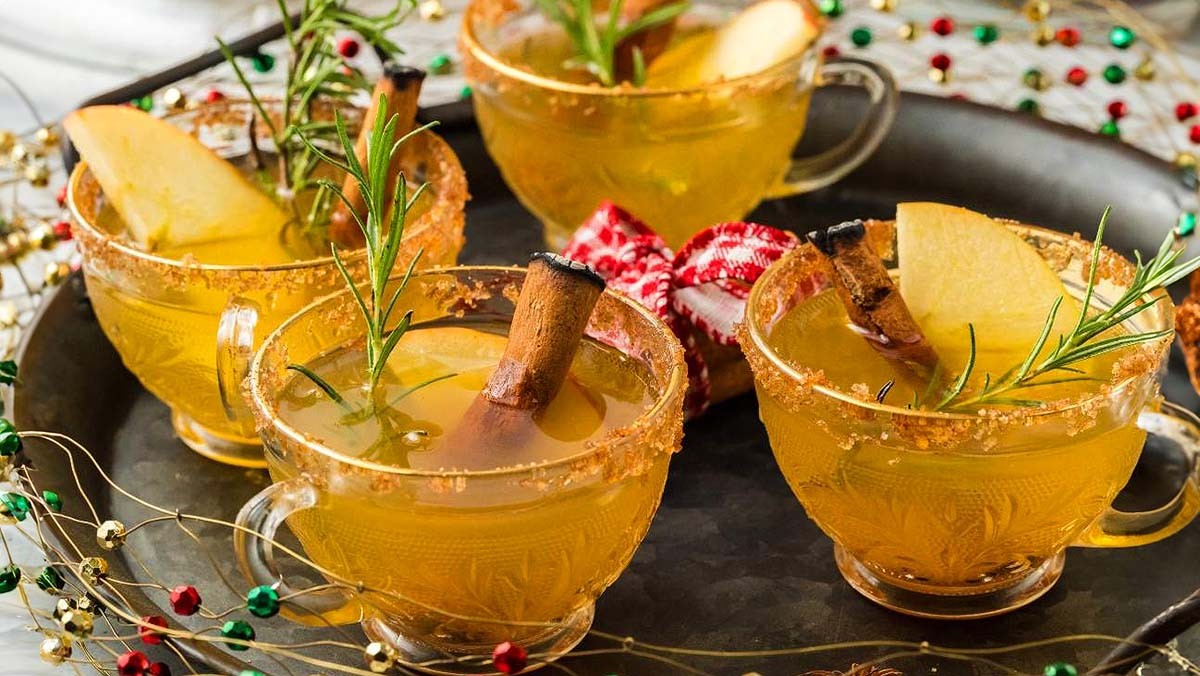 festive orange clove punch in a glass dispenser with holiday decor
