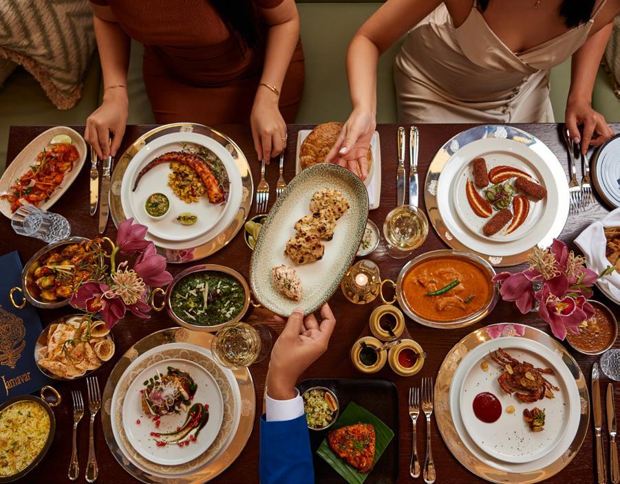 Overhead shot of a beautifully styled table setting with several bowls of rice raspberry rose pudding, garnished with fresh raspberries and rose petals, with soft natural light.
