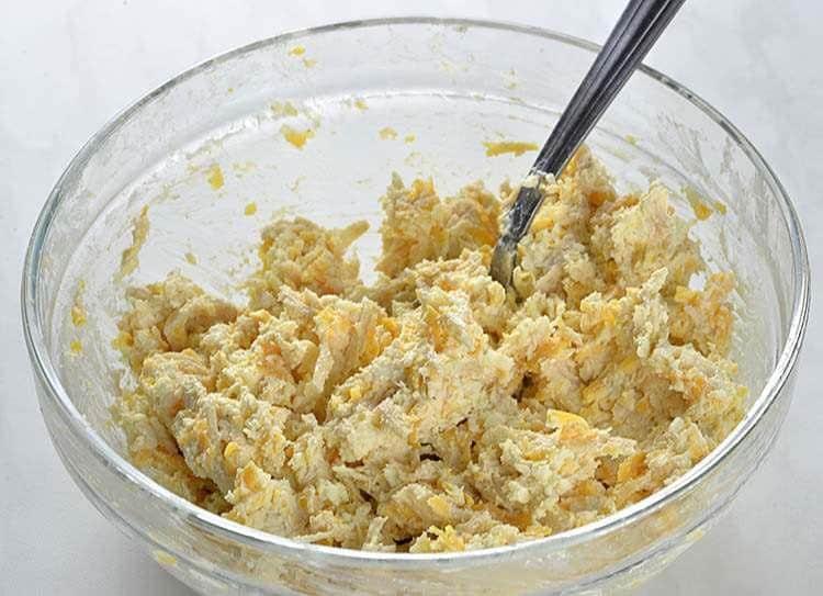 bowl of cookie dough with shredded chicken and parmesan cheese being mixed