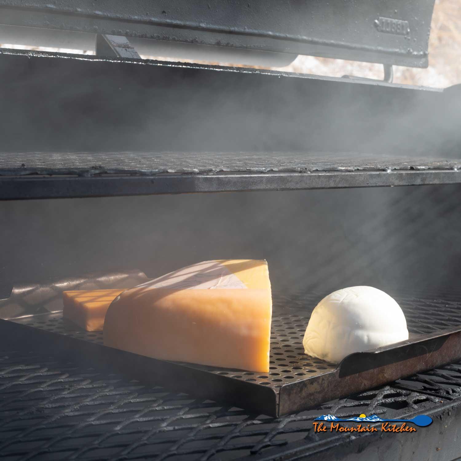 Close-up shot of a hand placing cheese blocks on a smoker rack