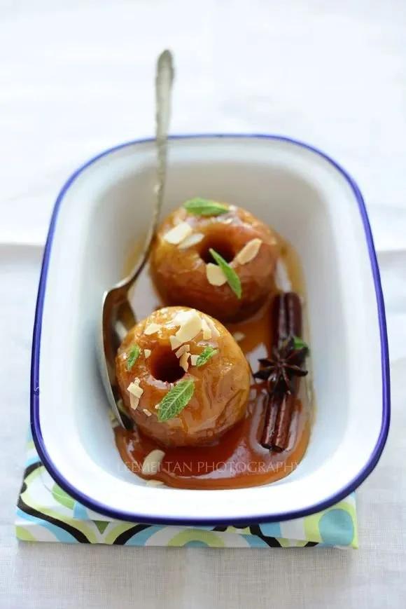 overhead shot of a baking dish with baked apples, cinnamon sticks, and star anise