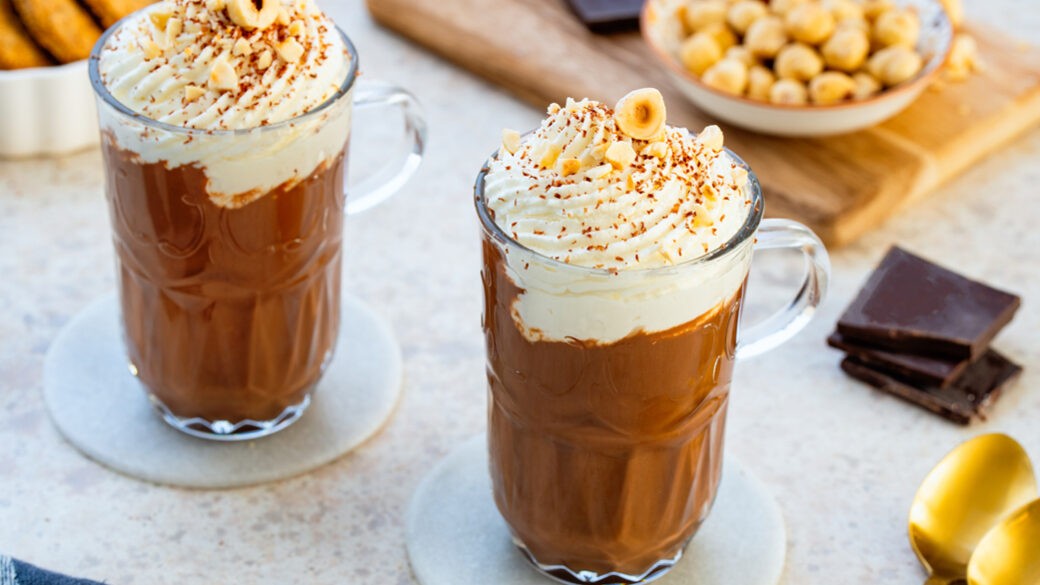 Gourmet hazelnut hot chocolate with whipped cream and chopped hazelnuts, cozy setting