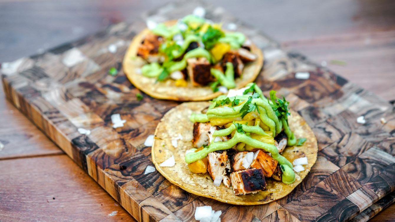 grilled chicken and pineapple tacos on a wooden board