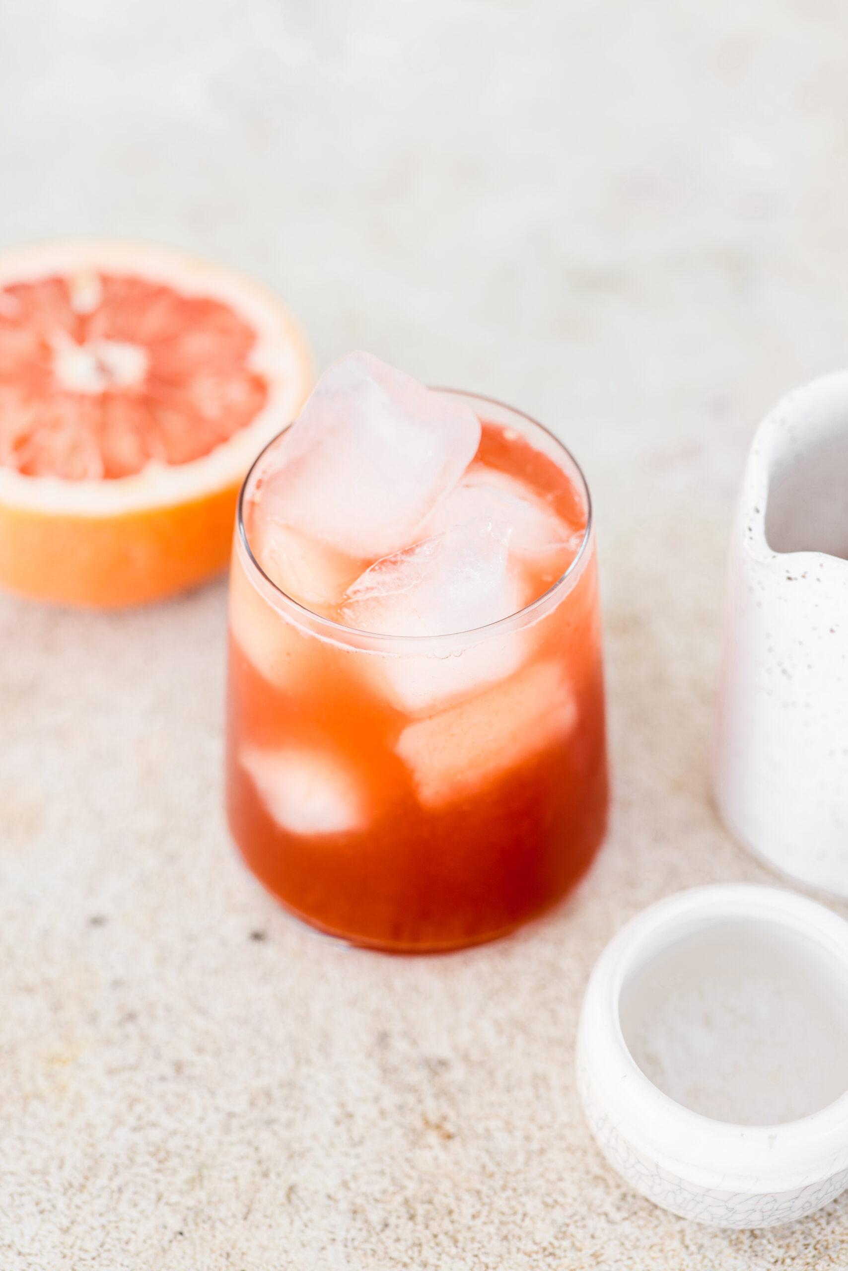a bowl of goji berries next to a halved grapefruit