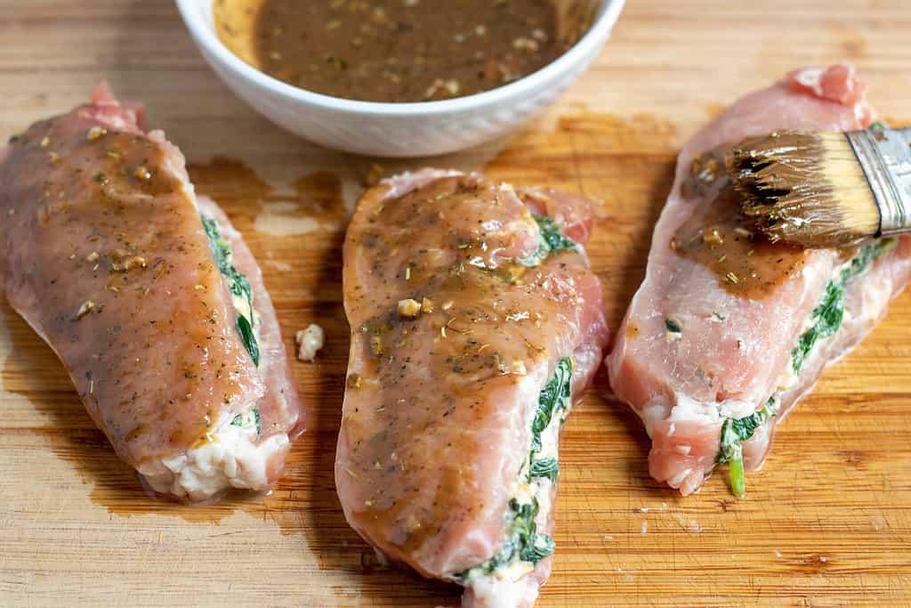 spinach and artichoke stuffed pork chops on a wooden cutting board