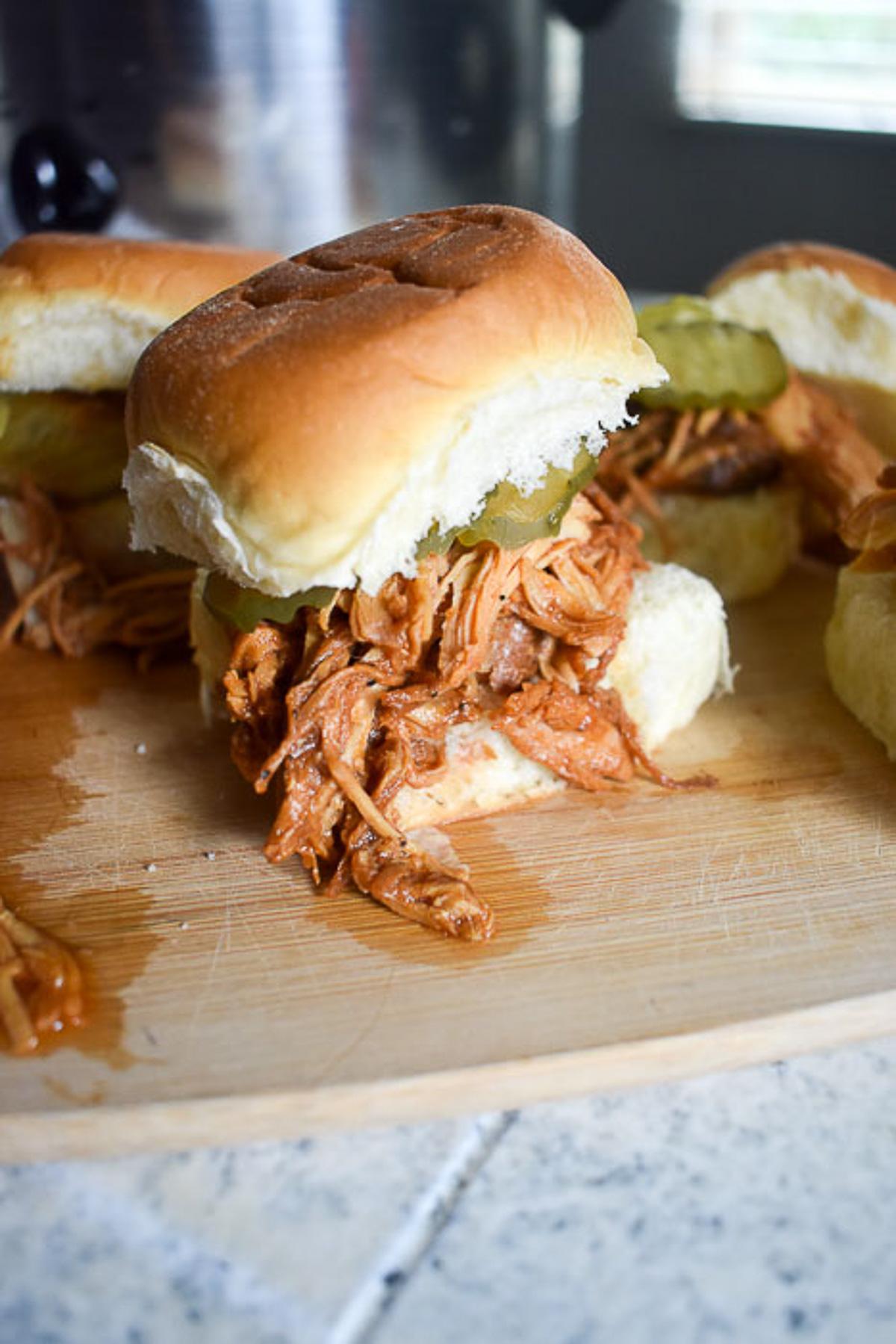 Crockpot blackberry BBQ chicken sliders on a picnic table