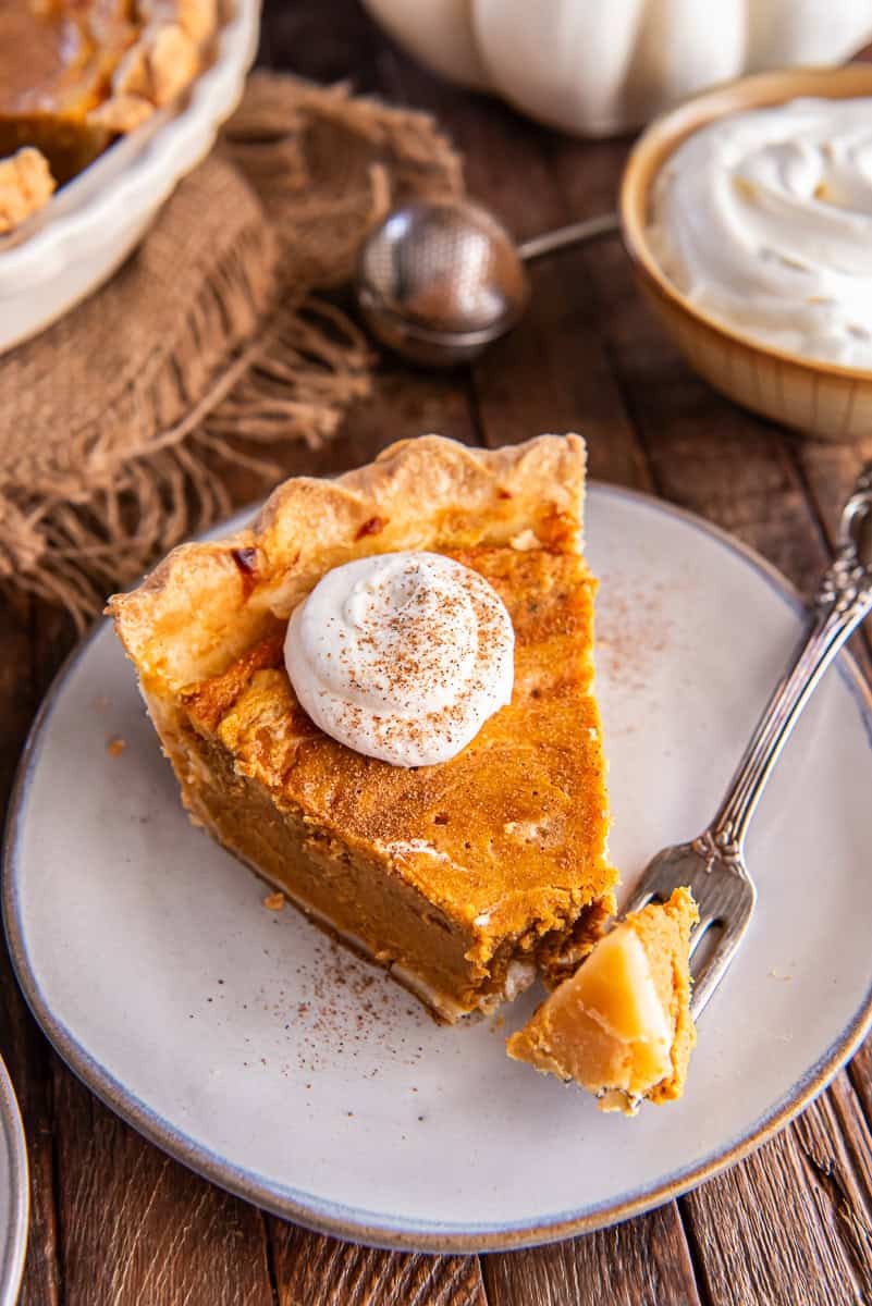 slice of creamy pumpkin pie with toasted spice crust on a rustic table with fall decor