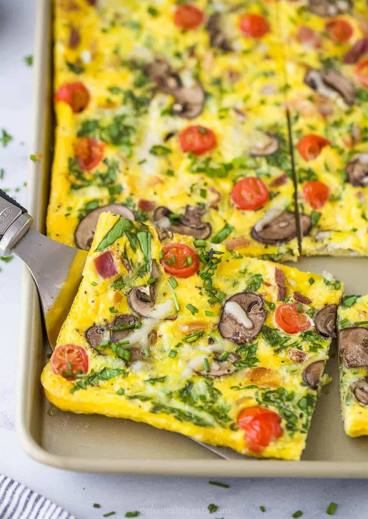 slice of mushroom and spinach frittata being lifted from the skillet with a spatula