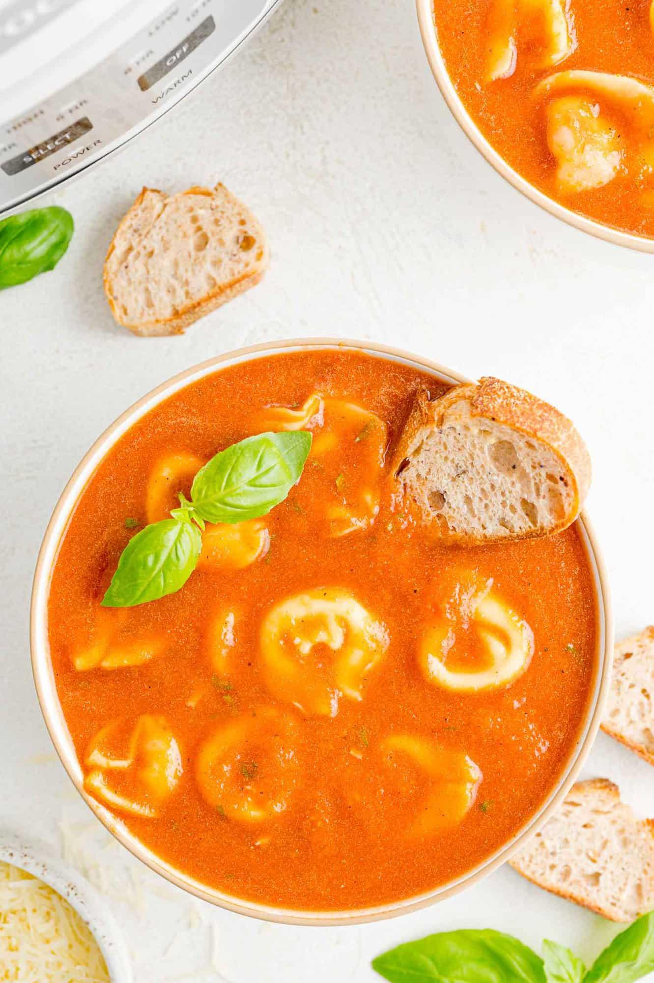 crockpot creamy tomato tortellini soup in a bowl with basil garnish