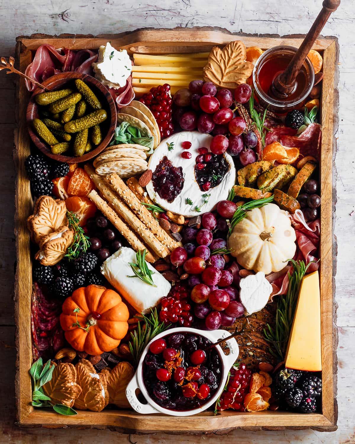 overhead shot of a beautifully arranged charcuterie board with fall-themed decorations